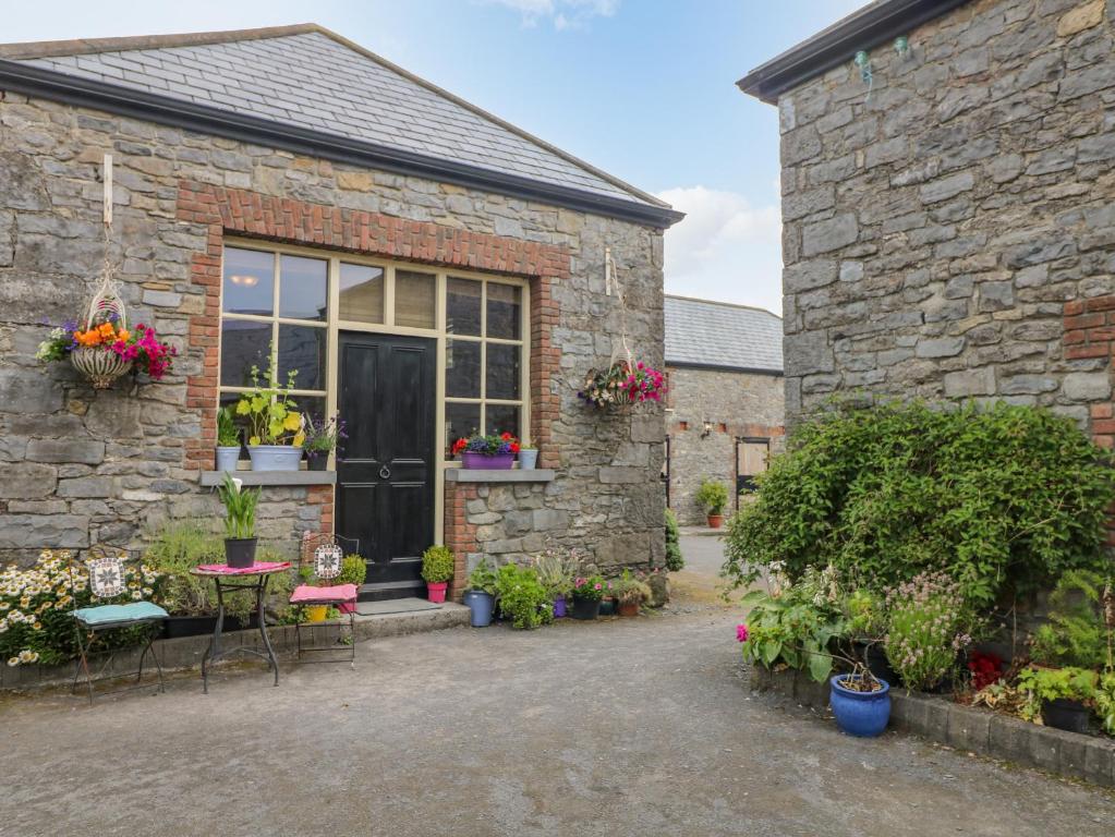 un edificio de ladrillo con mesa, sillas y plantas en Coach House en Portlaoise