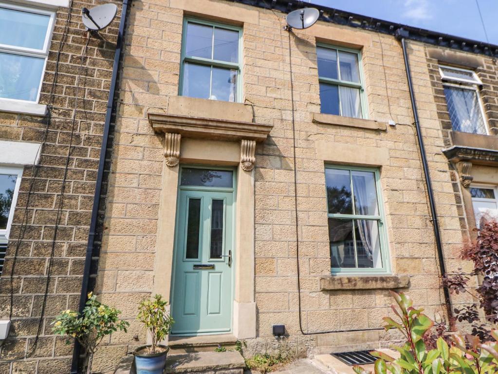 an old brick house with a green door at Beneath The Beams in Glossop