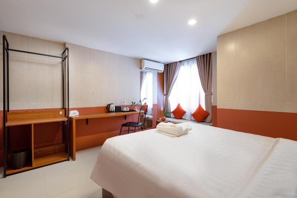a bedroom with a white bed and a desk and window at Hoianese Center Hotel - Truly Hoi An in Hoi An