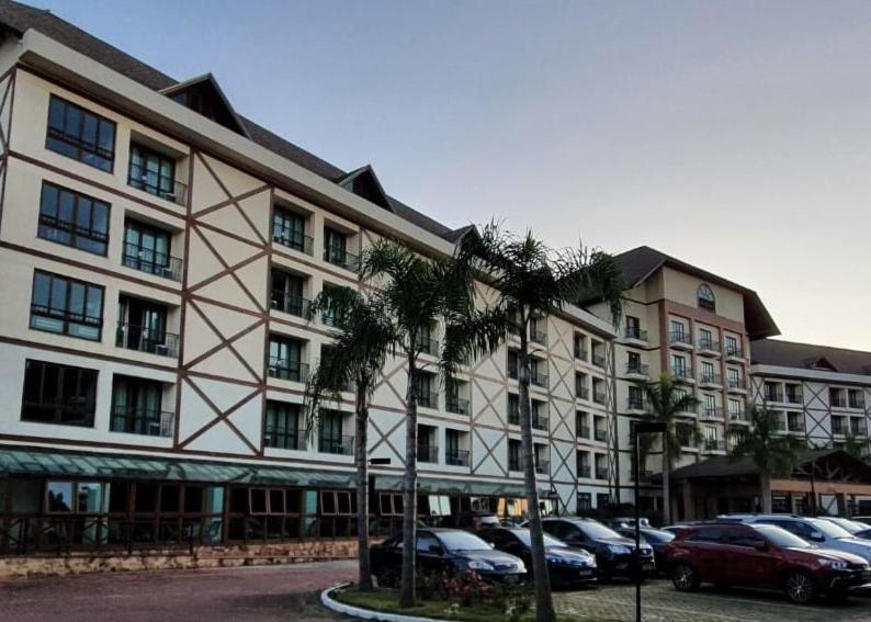 Condomínio Vista Azul Hotel في بيدرا أزول: مبنى كبير به سيارات تقف في موقف للسيارات