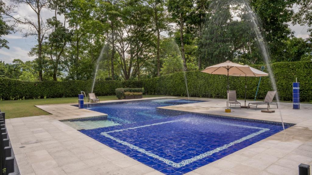 una piscina con sombrilla y fuente de agua en Hotel Palo Grande CF Pereira en Pereira