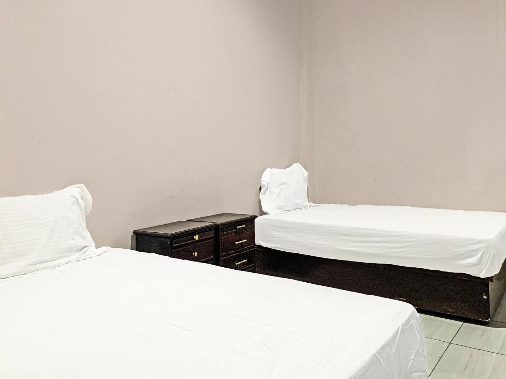 - 2 lits dans une chambre avec des draps blancs dans l'établissement OYO 91657 Penginapan Radja Jeneponto, à Pannara