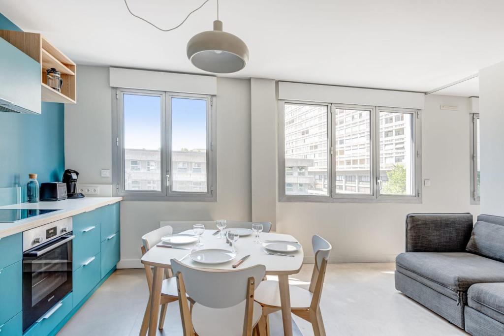 kuchnia i salon ze stołem i krzesłami w obiekcie Appartement Cyan - Welkeys w mieście Lyon