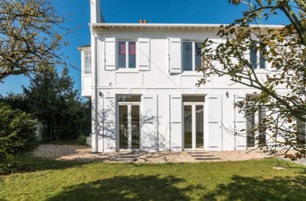 una casa blanca con una bandera roja en ella en Très jolie Villa Bianca, maison avec jardin privé à Deauville en Deauville