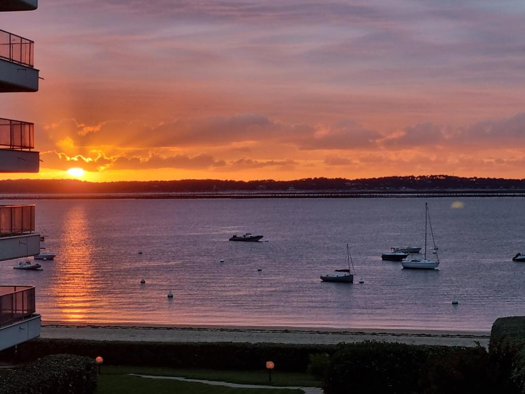 un coucher de soleil sur une grande étendue d'eau avec des bateaux dans l'établissement Superbe Vue mer T2bis Arcachon, à Arcachon