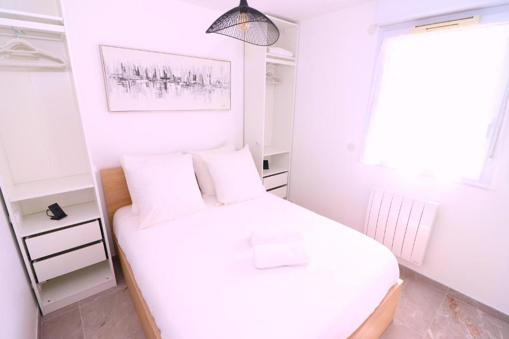 a small white bedroom with a bed and a window at La Cosy House in Evry-Courcouronnes