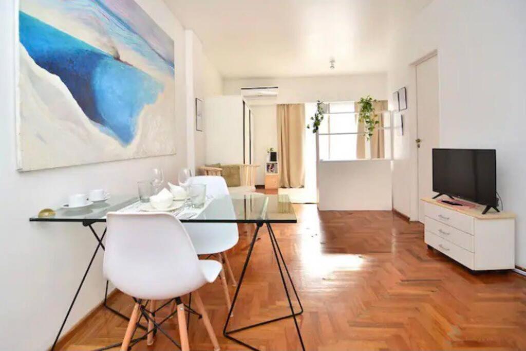 een woonkamer met een glazen tafel en witte stoelen bij Luxury Cañitas hermoso monoambiente in Buenos Aires