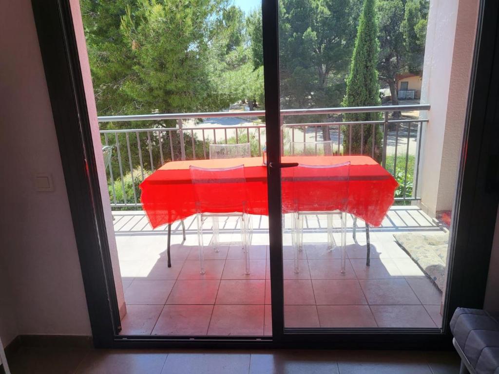 a red table on a balcony with a glass door at Apartamento Calafat, a 2 minutos a pie de Cala Llobeta in Calafat