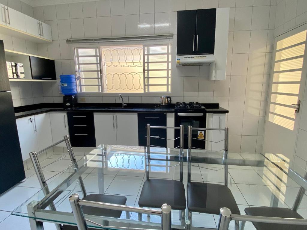 uma cozinha com uma mesa de vidro e cadeiras em Área Central/3 quartos/grande grupos em Marília