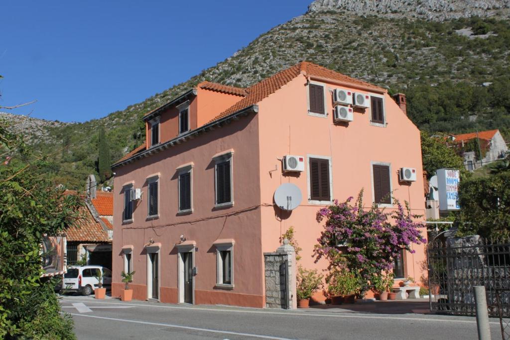 een gebouw aan de kant van een straat met een berg bij Rooms with a parking space Trsteno, Dubrovnik - 8595 in Trsteno