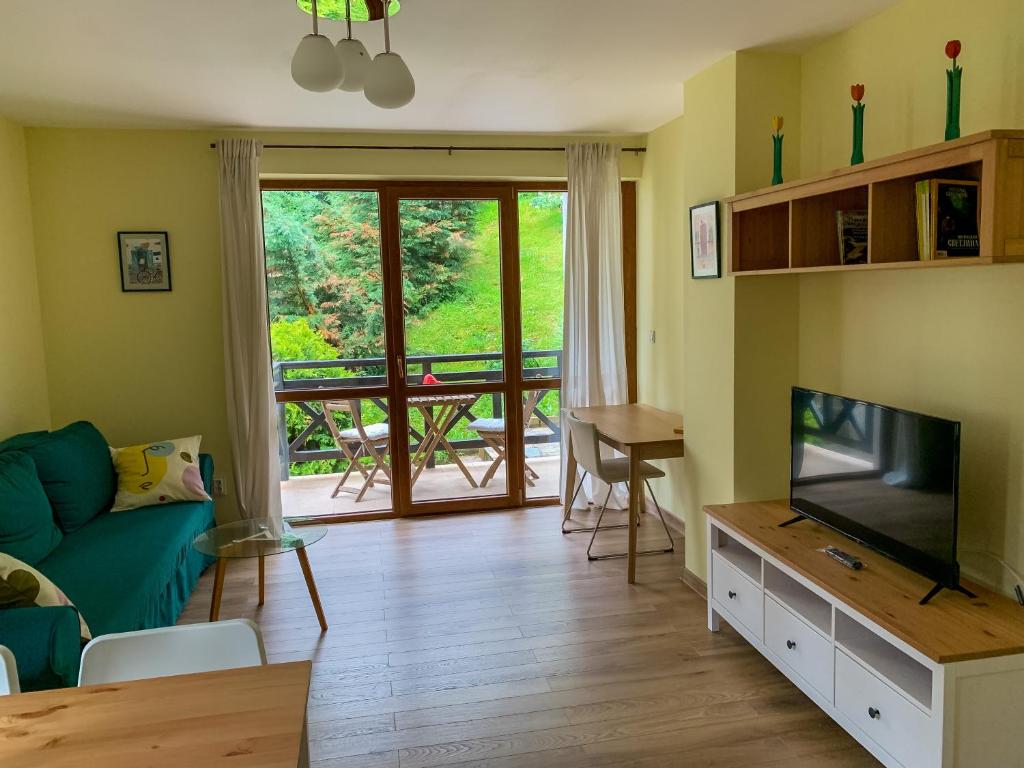 ein Wohnzimmer mit einem Sofa und einem TV in der Unterkunft Lovely forest escape, Mountain Lake complex in Smoljan