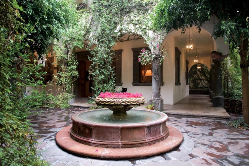 a fountain in front of a house with pink flowers at Casa Mision de San Miguel in San Miguel de Allende
