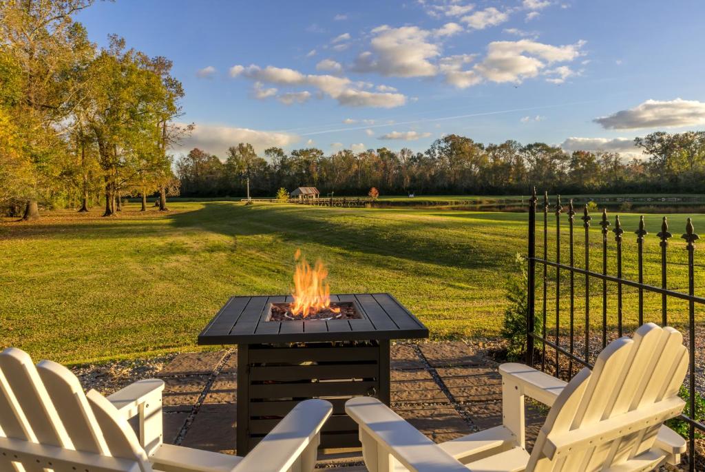 a fire pit in a yard with chairs and a fence at Maison D'Memoire Bed & Breakfast Cottages in Rayne