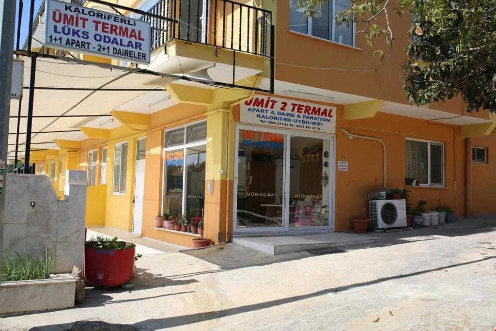 a store front of a yellow building on a street at Ümit 2 Termal Apart Pansiyon in Pamukkale