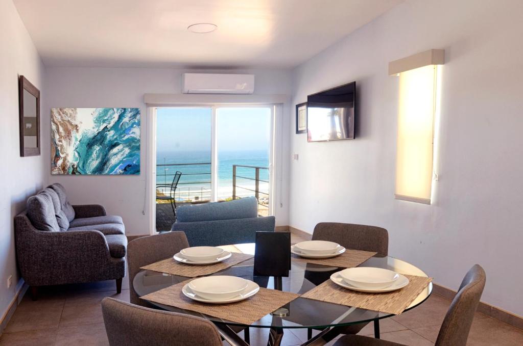 Sala de estar con mesa y sillas y vistas al océano en Popotla Villa #204, en Divisadero
