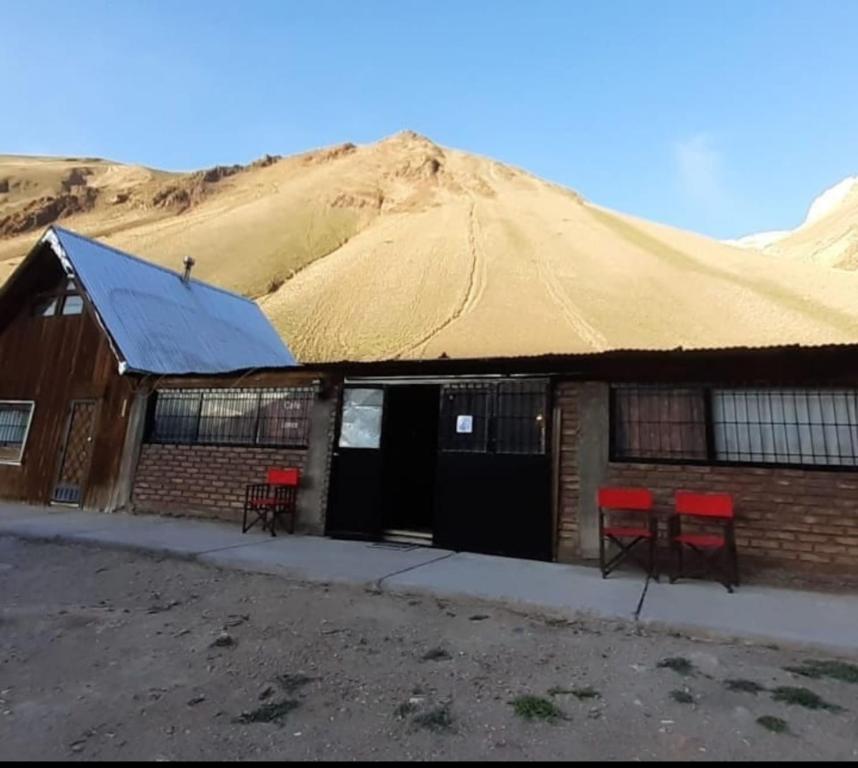 a building with red chairs and a thatched roof at Altas Cumbres Penitentes in Los Penitentes