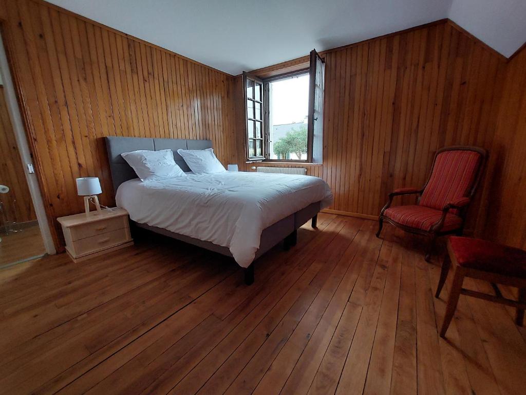 um quarto com uma cama, uma cadeira e uma janela em chez Jean-Marc et Colette em Le Molay-Littry