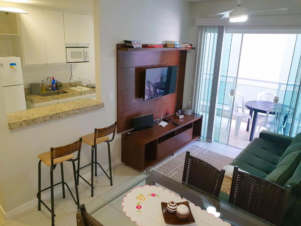 a living room with a couch and a tv and a kitchen at AP Praia do Forte! Charme e conforto!(104) in Cabo Frio