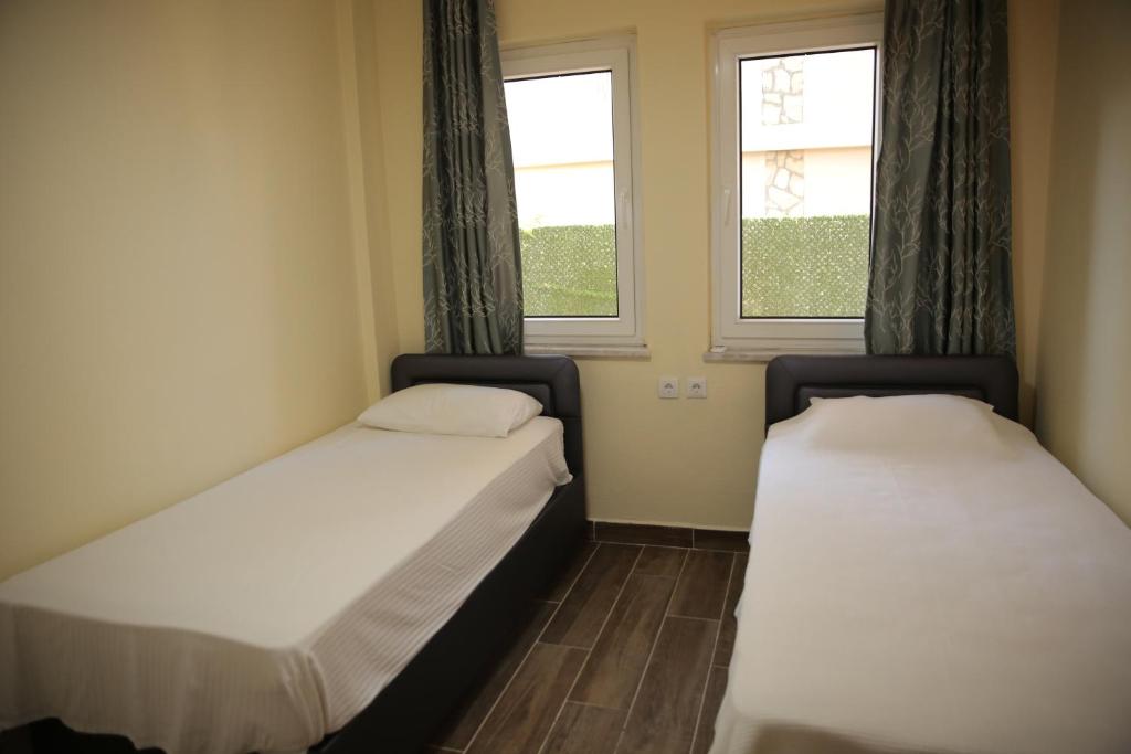 2 Betten in einem kleinen Zimmer mit 2 Fenstern in der Unterkunft Villa Verdi in Dalyan