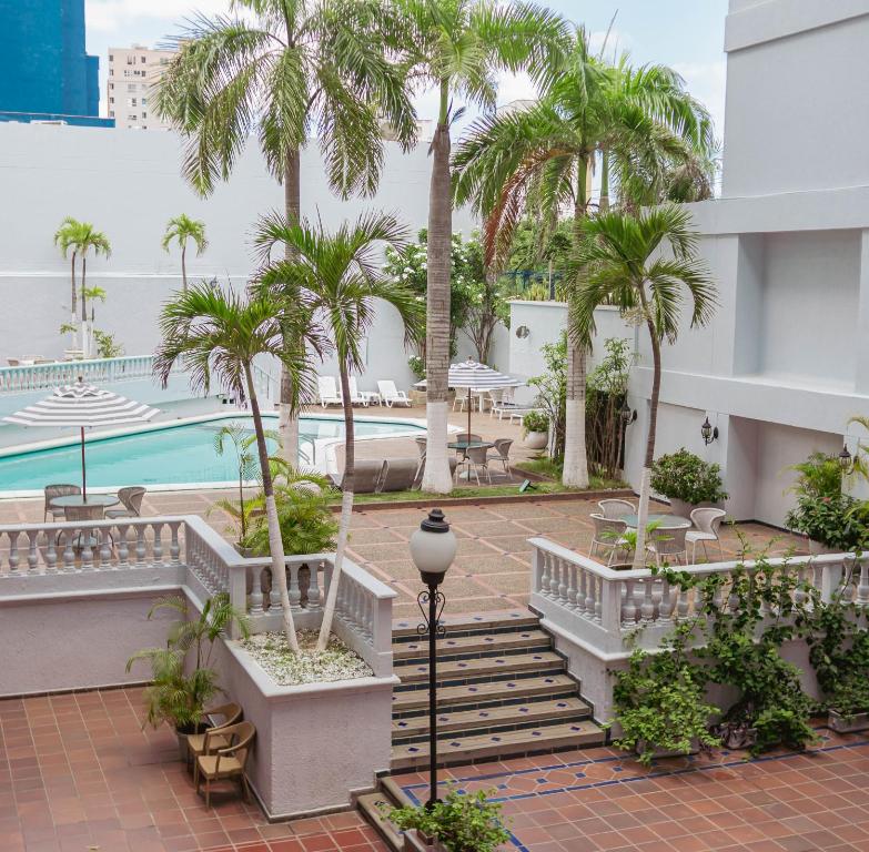 un complexe avec des palmiers et une piscine dans l'établissement Hotel Faranda Express Puerta Del Sol Barranquilla, A Member of Radisson Individuals, à Barranquilla