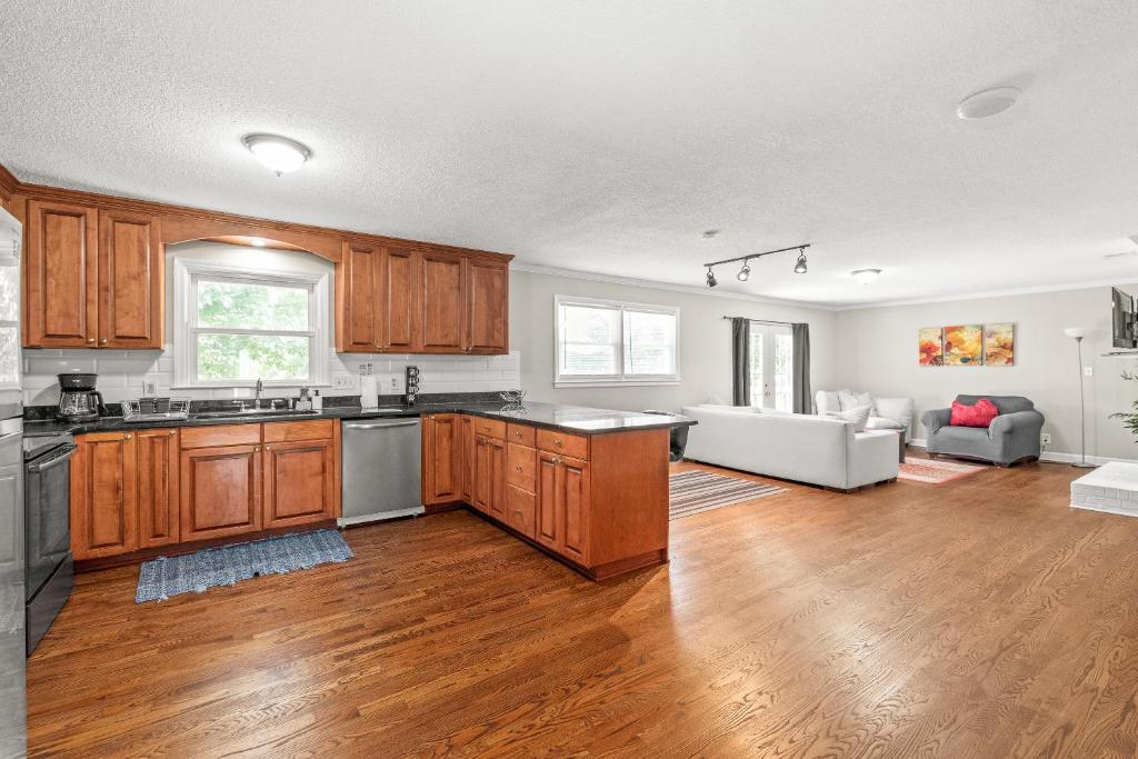a kitchen with wooden cabinets and a living room at Charming, Cozy Home close to Uptown, Airport & Whitewater Center in Charlotte