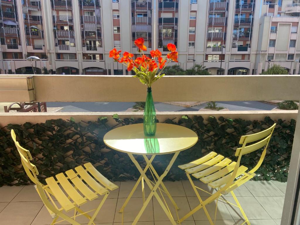 un vase de fleurs assis sur une table avec deux chaises dans l'établissement Nice Port , 2BR, 6 Guests, Walk to Beach and Old Town, à Nice