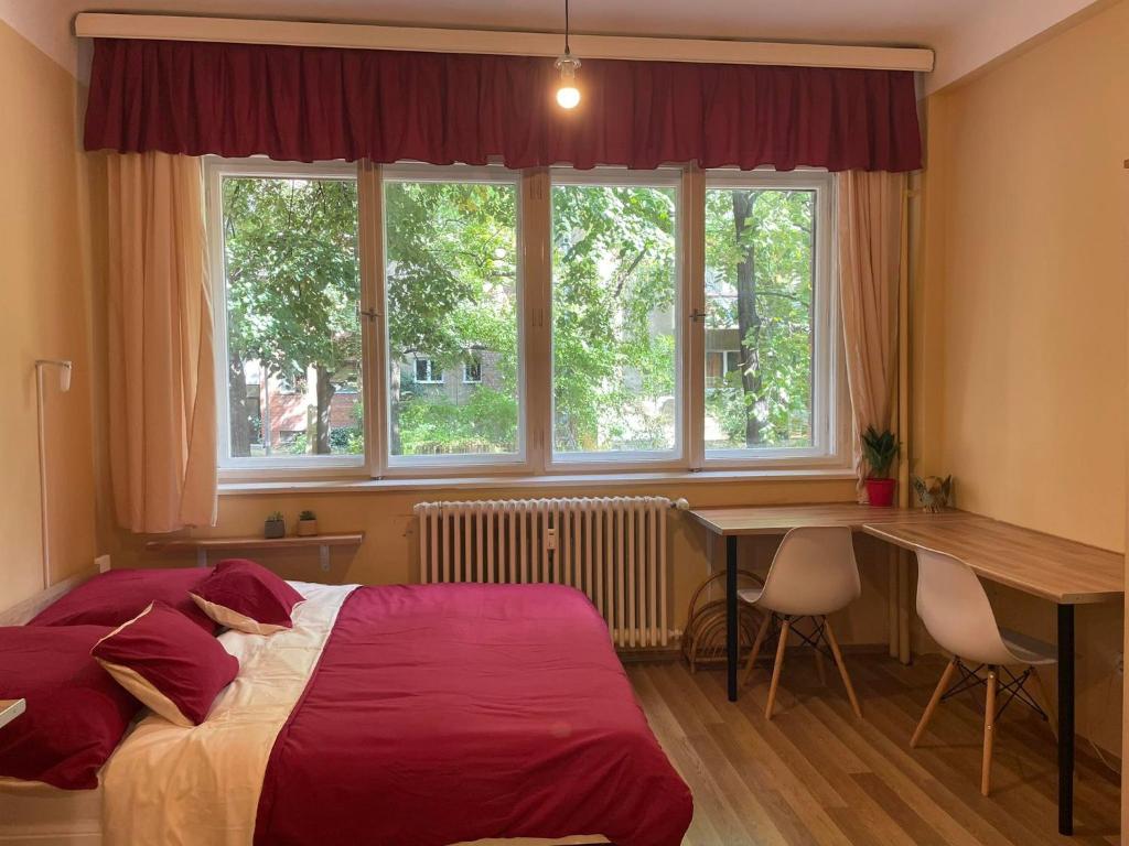 a bedroom with a bed and a desk and windows at Home in the Heart in Budapest