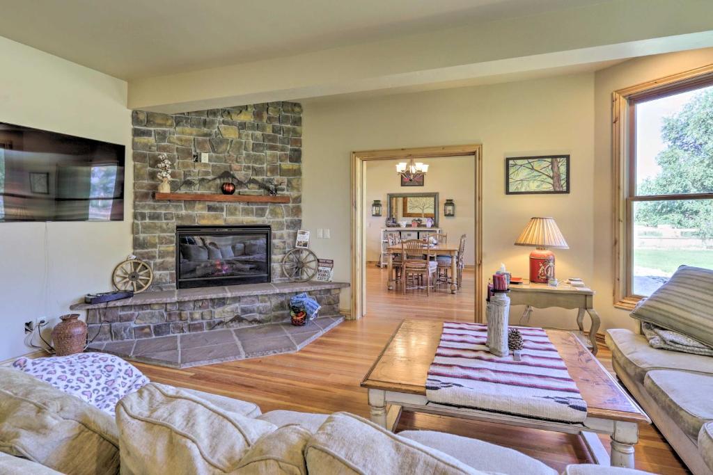 a living room with a stone fireplace and a table at Fruita Victorian Home with Hot Tub and Mountains! in Fruita
