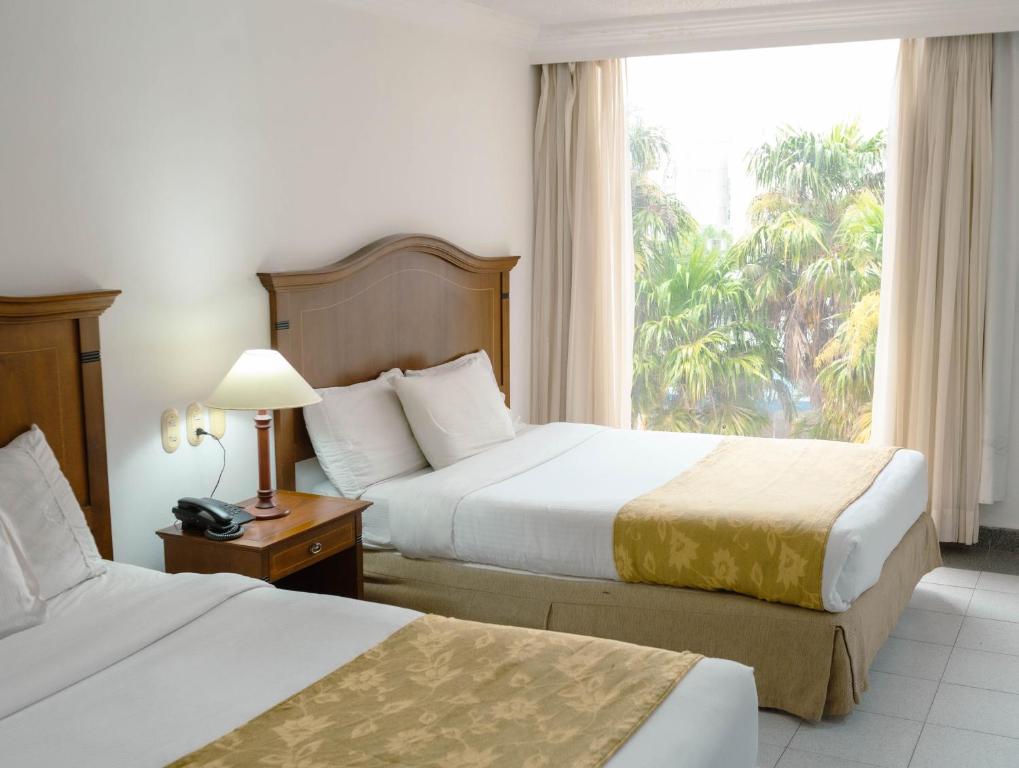 a hotel room with two beds and a window at Hotel Faranda Express Puerta Del Sol Barranquilla, A Member of Radisson Individuals in Barranquilla