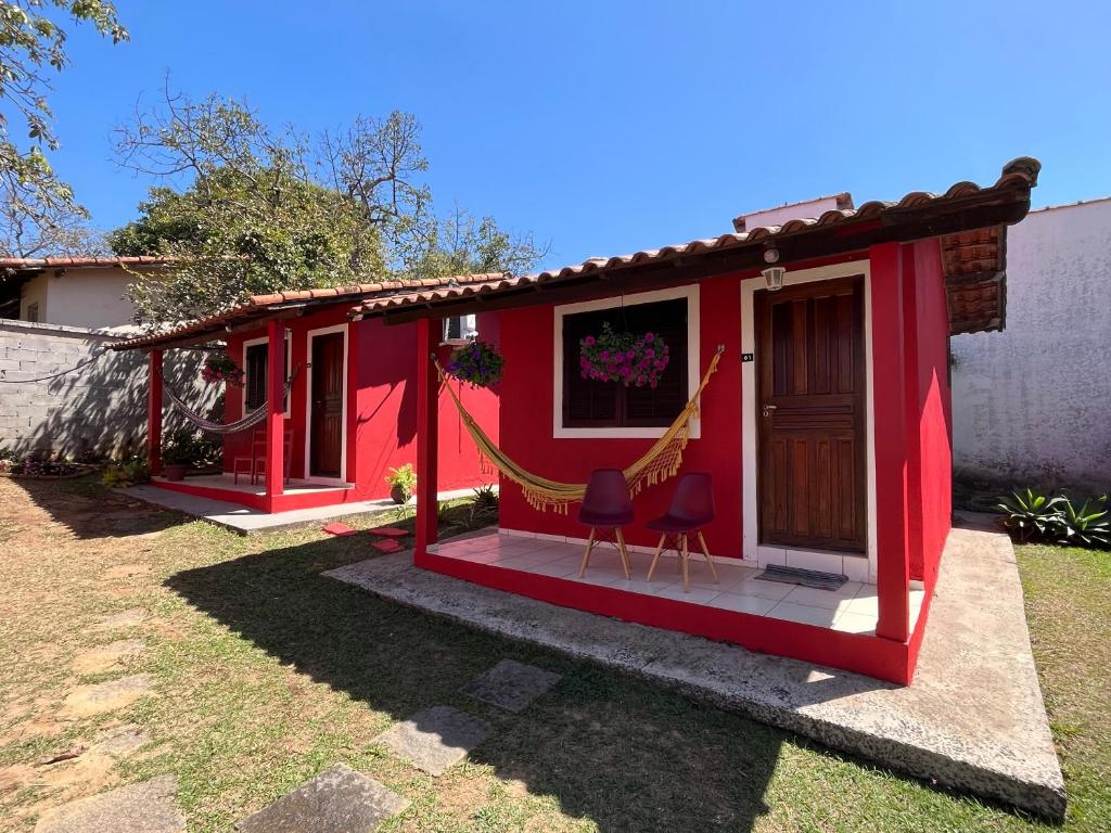 a red tiny house with two chairs in the yard at Vila Noel Centro in Penedo