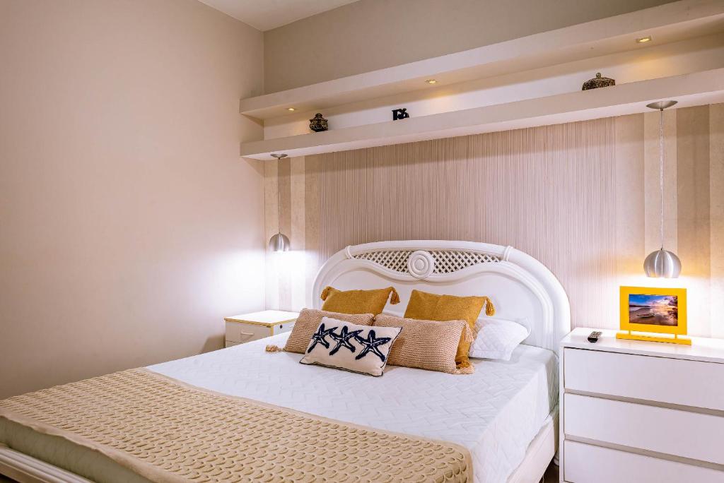 Un dormitorio con una cama blanca con almohadas. en VARANDA GOURMET c churrasqueira-3 quartos- Wi-fi, en Bertioga