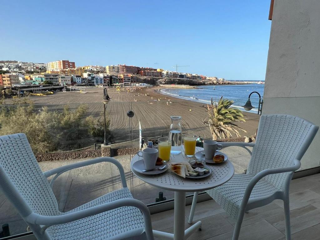einen Tisch mit Speisen und Getränken auf einem Balkon mit Strand in der Unterkunft Vistasmelenara in Telde