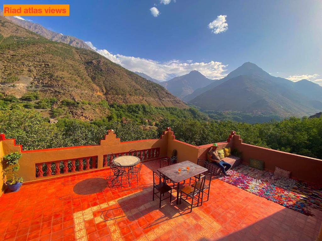 d'un balcon avec une table, des chaises et des montagnes. dans l'établissement Atlas Views, à Imlil