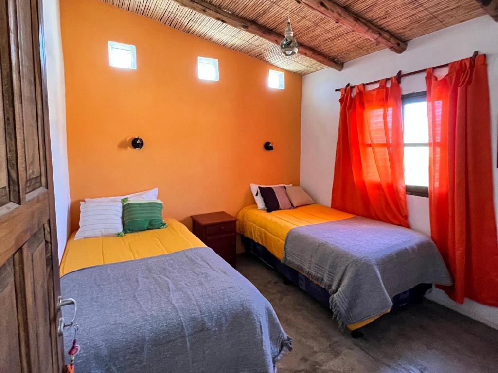 - 2 lits dans une chambre aux murs orange dans l'établissement Cabaña Paraíso Cachi, à Cachí