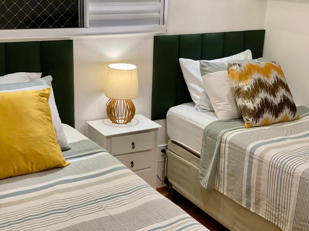 duas camas num quarto com um candeeiro numa mesa de cabeceira em VILA INDUSTRIAL/C/AR CONDICIONADO em Marília