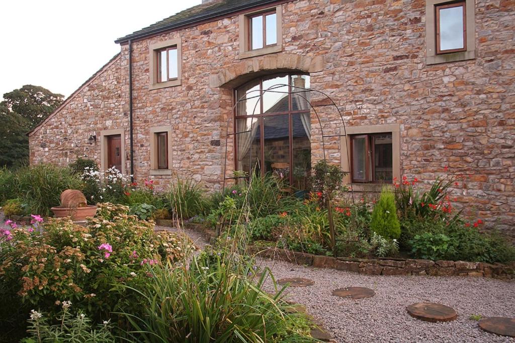 a stone house with a garden in front of it at Foxhill Barn in Gisburn