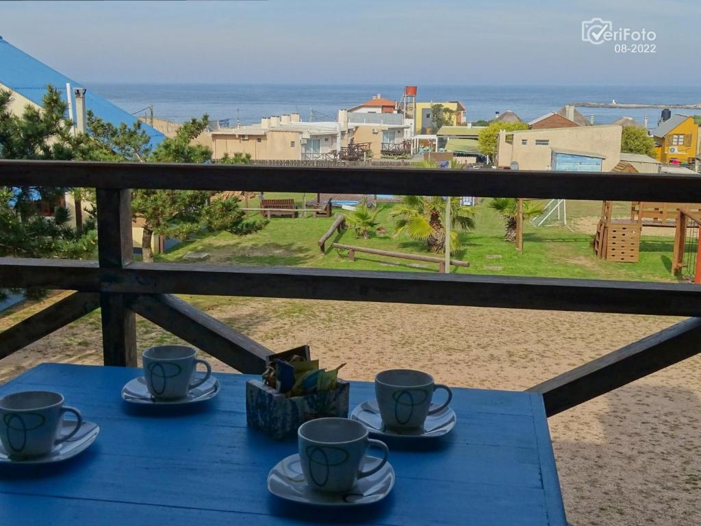 una mesa azul con tazas y platillos en el balcón en Complejo Dunas del Diablo, en Punta del Diablo