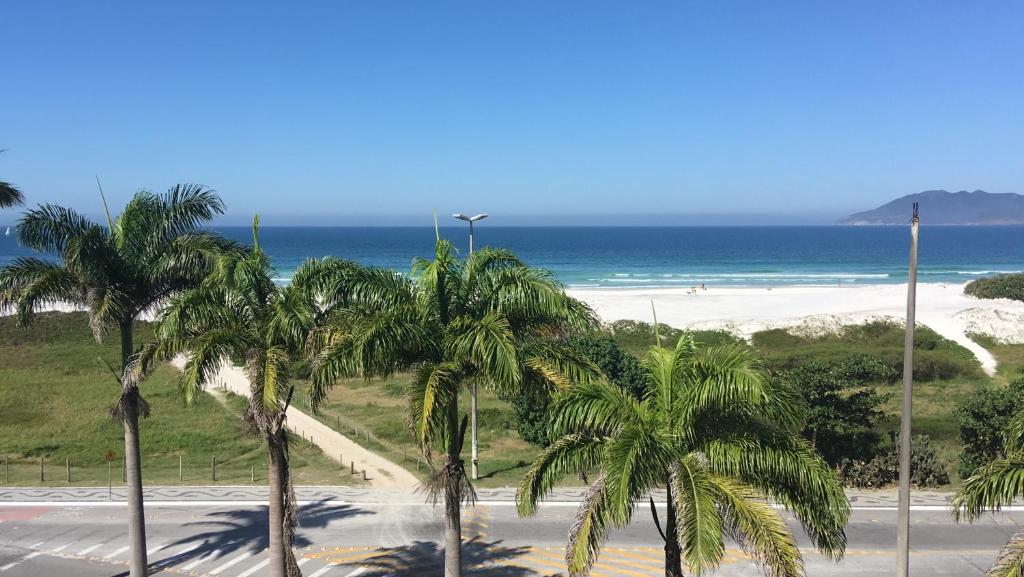 a view of a beach with palm trees and the ocean at Apartamento - CARIBE BRASILEIRO - Praia do Forte - De frente para o mar in Cabo Frio