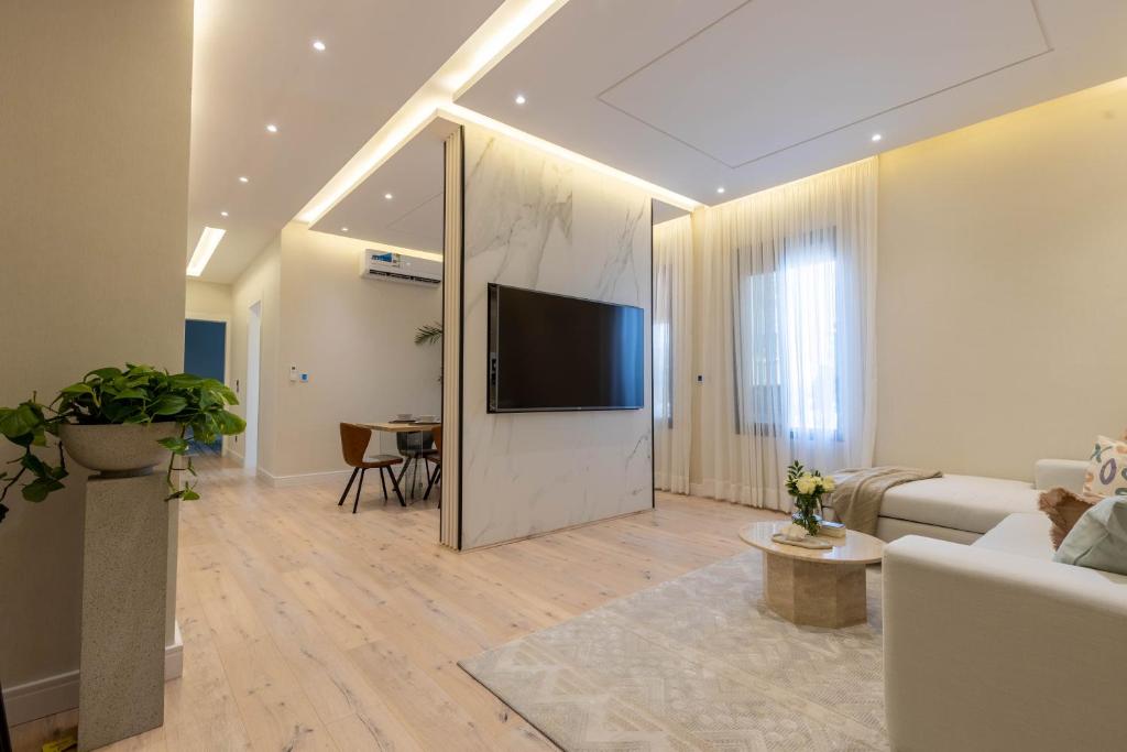 Spacious and Modern Apartment for Rent in Ergah, Riyadh في الرياض: غرفة معيشة مع تلفزيون بشاشة مسطحة وأريكة