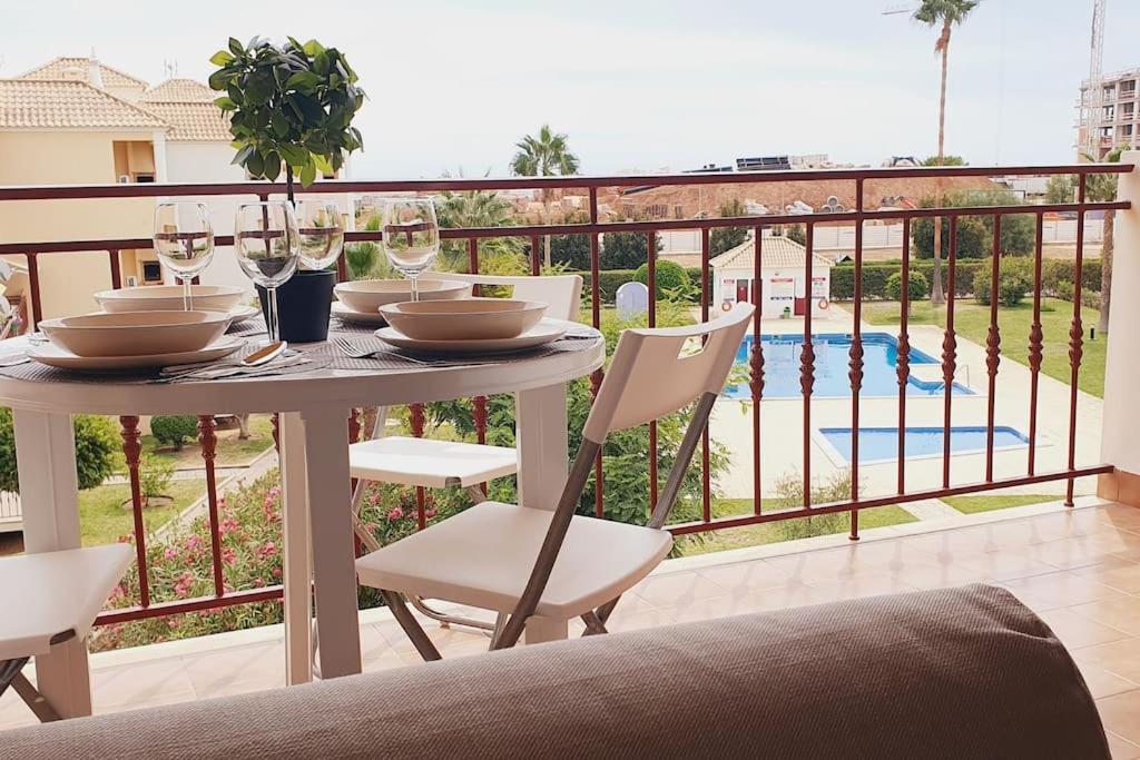 una mesa con sillas y copas de vino en el balcón en Lindo apartamento junto à praia e à Marina de Vilamoura com Piscina e Wi-Fi, en Quarteira
