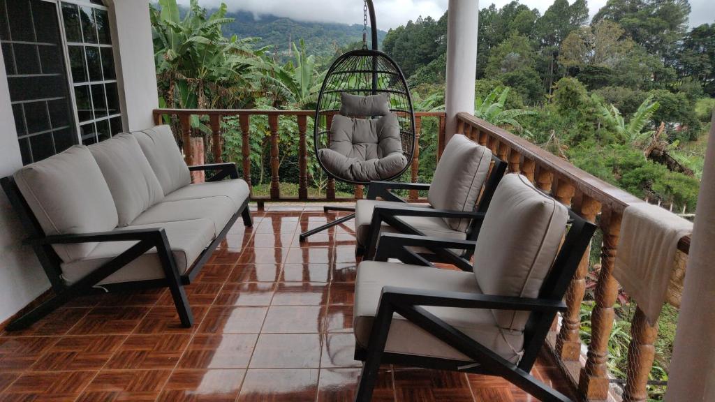 a porch with two chairs and a swing at Agartha Hostel in Boquete
