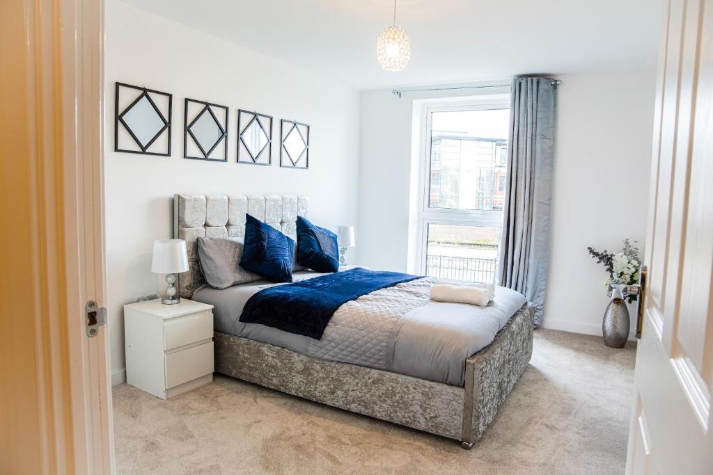 ein Schlafzimmer mit einem Bett mit blauen Kissen und einem Fenster in der Unterkunft A luxury 2 bedroom apartment with 2 free parking in Chatham