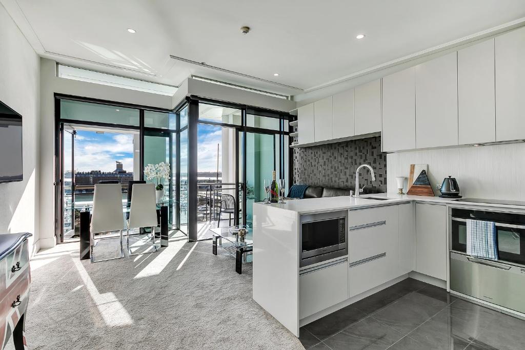 uma cozinha com armários brancos e uma sala de estar em Penthouse Premier em Auckland