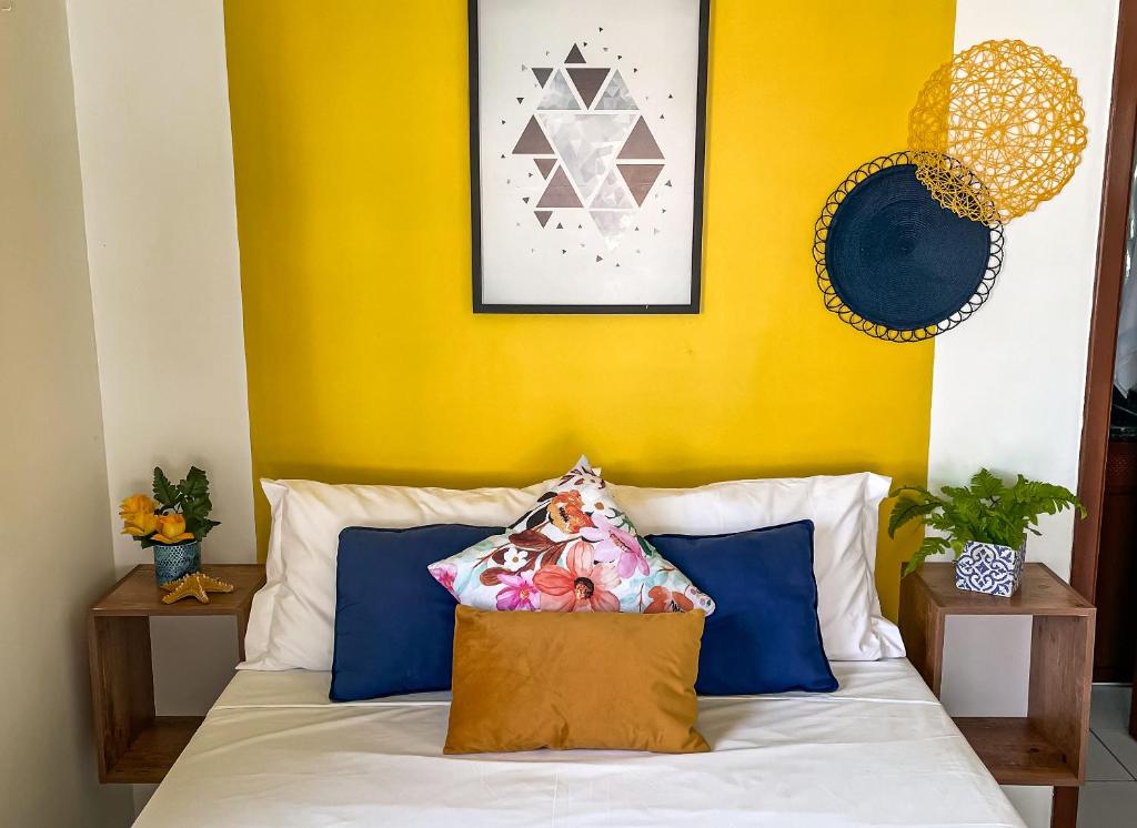 a bedroom with a yellow wall and a bed with blue pillows at Suíte com Banheira, próximo à Praia Litorânea Limão Siciliano Limoneto House Eventos, Hostel e Pousada in São Luís