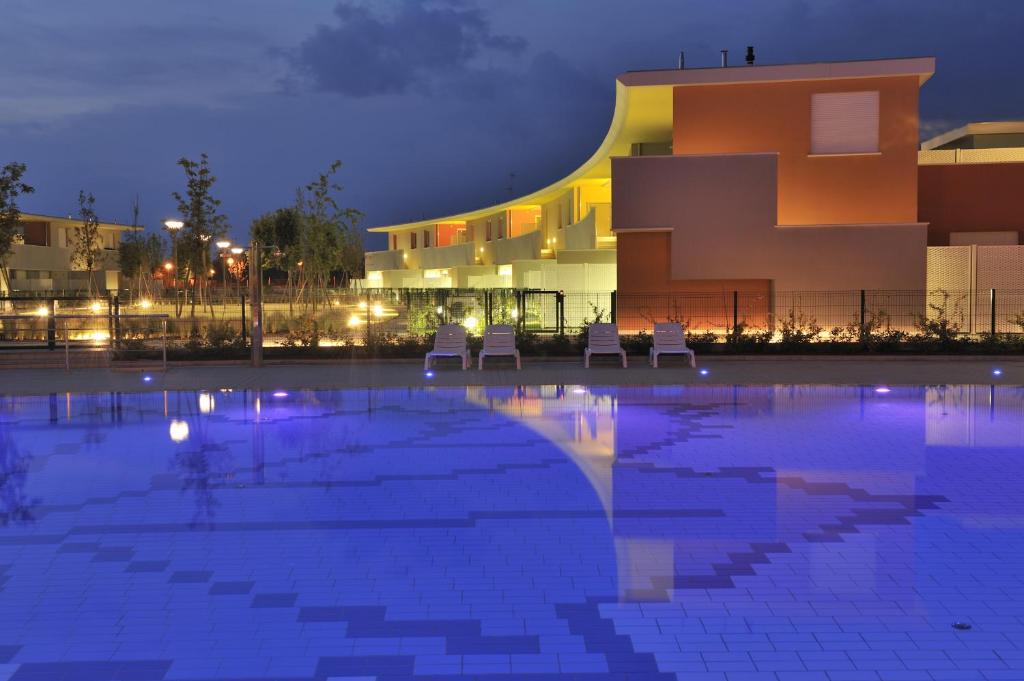 a swimming pool in front of a building at night at Bosco dell'Impero Nettuno in Bibione