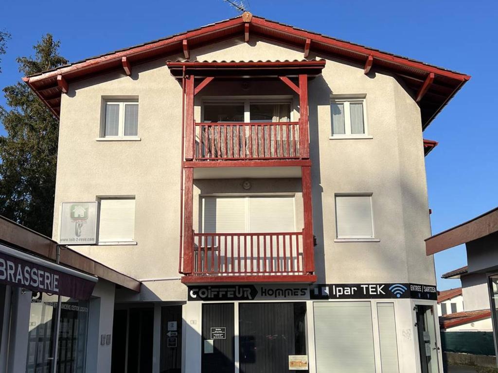 un bâtiment avec un balcon au-dessus dans l'établissement T2 calme avec terrasse, parking privatif, cuisine équipée, centre de Cambo-les-Bains - FR-1-495-112, à Cambo-les-Bains