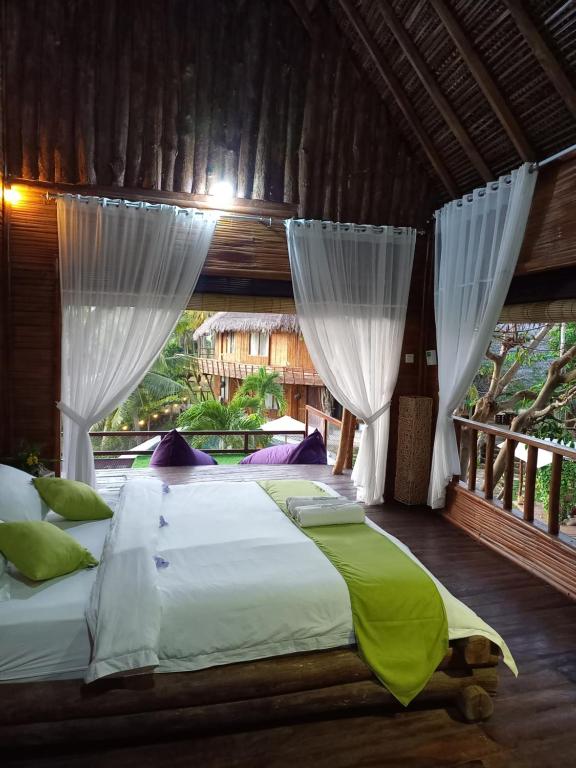 Schlafzimmer mit einem großen Bett und weißen Vorhängen in der Unterkunft Gading Tree House in Nusa Penida