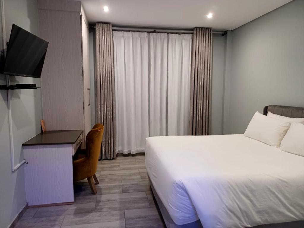 um quarto com uma cama, uma secretária e uma televisão em Heavenly Towers em Mbazwana