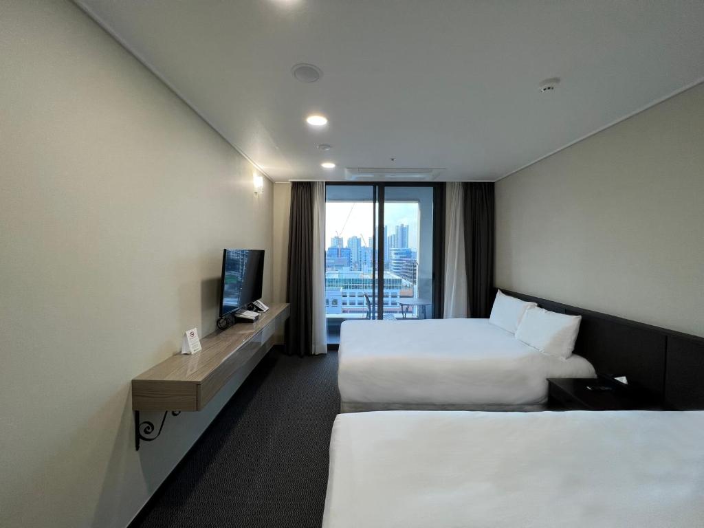 een hotelkamer met 2 bedden en een raam bij Incheon Rivieraverium Hotel in Incheon