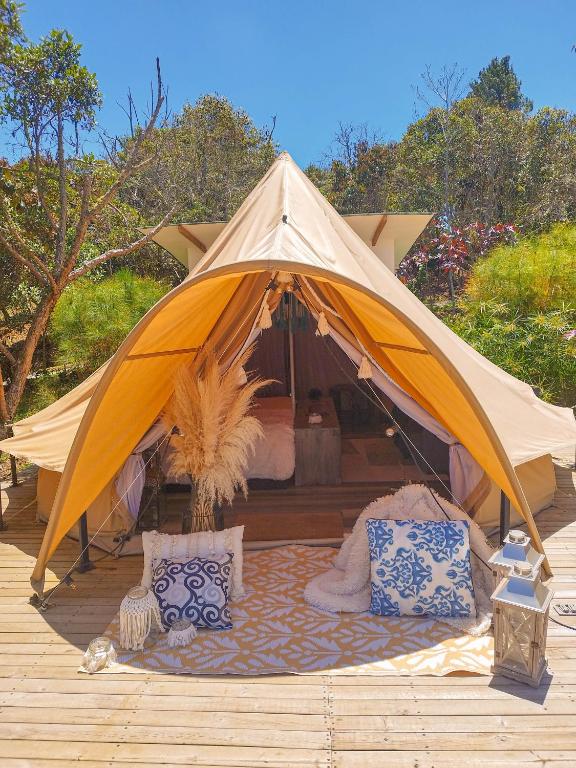 una tenda con un letto e cuscini su un ponte di AKOA GLAMPING Eco-Luxury Hotel a Guarne